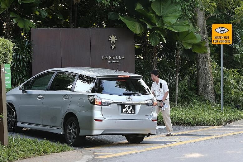 Additional security cameras were seen being put up on Sentosa ahead of the summit. A queue of cars (above) in Sentosa Cove yesterday amid heightened security. At Capella hotel (right), security staff were stationed at the entrance to screen visitors.