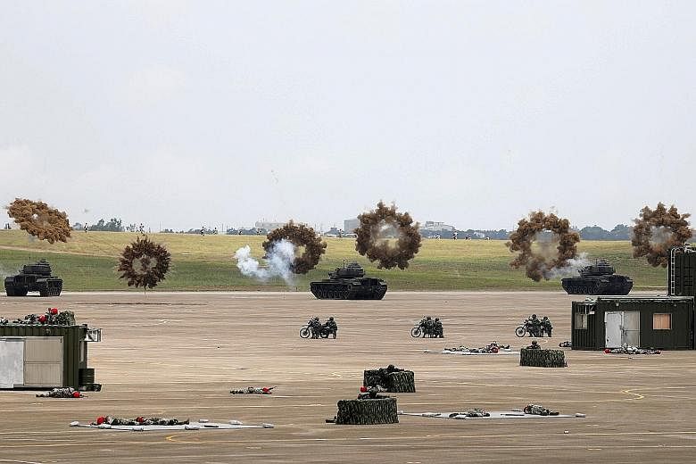 Tanks firing smoke bombs during the "Han Kuang" military exercise at the Ching Chuan Kang Air Base, in Taichung, Taiwan, yesterday. More than 4,000 personnel and over 1,500 pieces of equipment were deployed in the annual exercise.