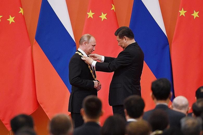 Left: Chinese President Xi Jinping presenting Russian President Vladimir Putin with the Friendship Medal in Beijing yesterday. Above: The two leaders dropping the puck to start a friendly match between the Chinese and Russian youth ice hockey teams i