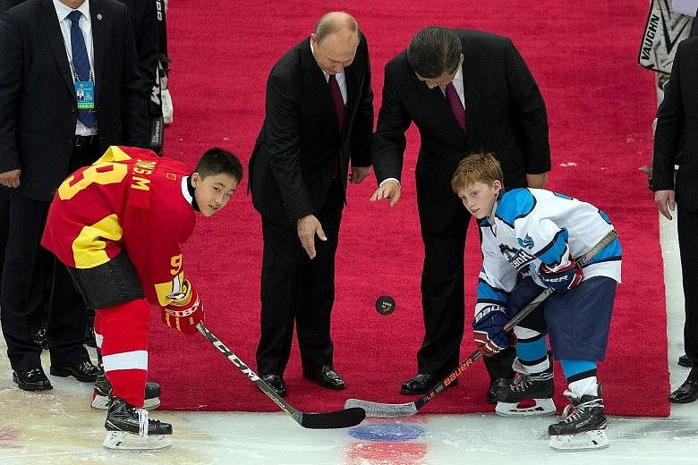 Left: Chinese President Xi Jinping presenting Russian President Vladimir Putin with the Friendship Medal in Beijing yesterday. Above: The two leaders dropping the puck to start a friendly match between the Chinese and Russian youth ice hockey teams i