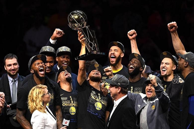 Stephen Curry lifting the Larry O'Brien trophy to his team-mates' cheers after the Golden State Warriors beat the Cleveland Cavaliers 108-85 in Game 4 to win the NBA Finals for the third time in four years.