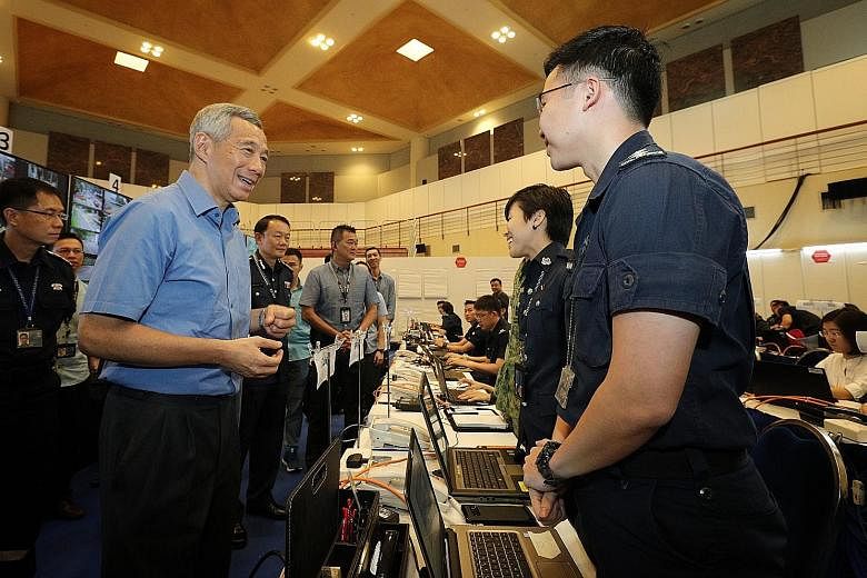 Prime Minister Lee Hsien Loong speaking to officers on duty during his visit to the Home Team command post in Novena yesterday. PM Lee with Chief of Defence Force Melvyn Ong (left) and Director of Joint Operations Tan Chee Wee on the rooftop of Sento