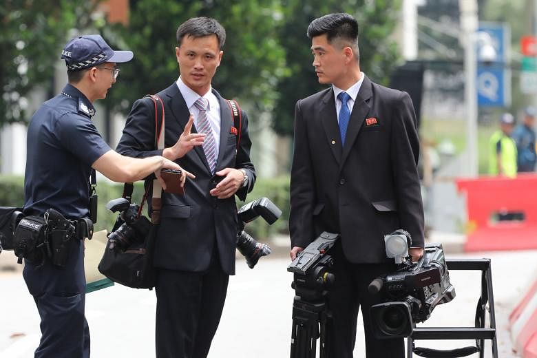 The two men in black suits, believed to be part of the North Korean delegation, in Tanglin Road yesterday. They were allowed onto two closed lanes of the four-lane road.