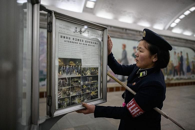 A conductor putting up the Rodong Sinmun newspaper, showing images of North Korean leader Kim Jong Un in Singapore, at a news-stand on a Pyongyang metro subway platform yesterday.