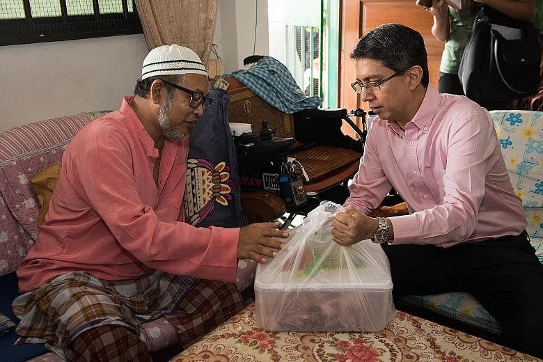 Dr Muhammad Faishal Ibrahim (right), Senior Parliamentary Secretary for the Ministry of Social and Family Development and Ministry of Education, giving fresh mutton to Mr Sulaiman Ismail during his home visit yesterday as part of the Meat For The Nee