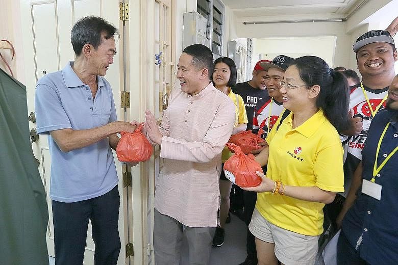 Senior Parliamentary Secretary and Sembawang GRC grassroots adviser Amrin Amin handing food to rental flat resident Lee Zhi Xin, 64. With him are Ms Wang Yi (right) and her daughter Zhao Jiayi. Over 100 volunteers packed food which was then delivered