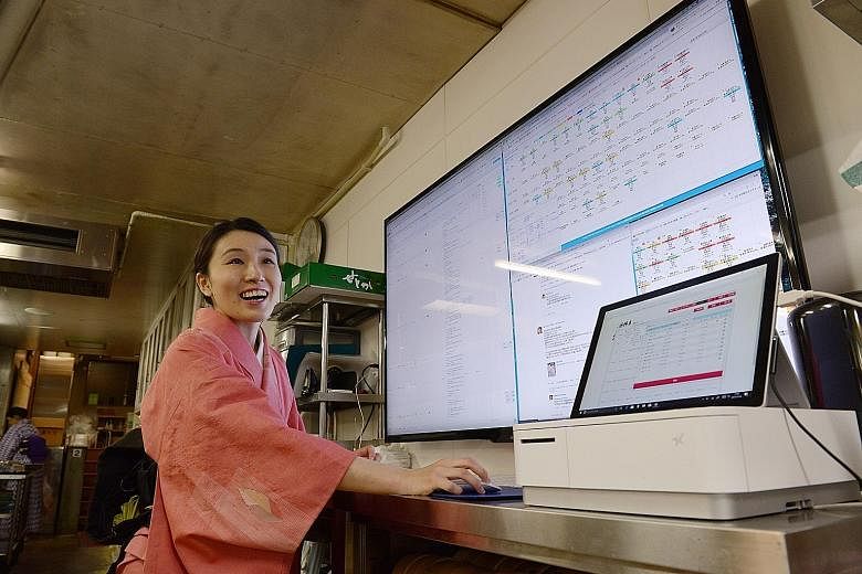 Staff members always carry a tablet to welcome guests personally. Mrs Tomoko Miyazaki, of the Jinya ryokan in Hadano, Kanagawa prefecture, in front of a monitor in its kitchen that shows information such as customer food preferences.