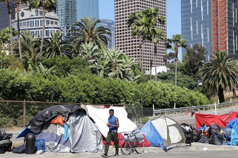 The tents of homeless people (above) lining a street leading into the burgeoning downtown skyline of Los Angeles, California. (Below) A homeless man in Worcester, Massachusetts.