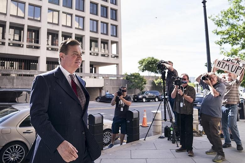 A protester holding up a sign as Paul Manafort, President Donald Trump's former campaign chairman, arrives at the federal courthouse in Washington for an arraignment hearing on Friday. The judge later ordered that he await trial in jail, a spectacula
