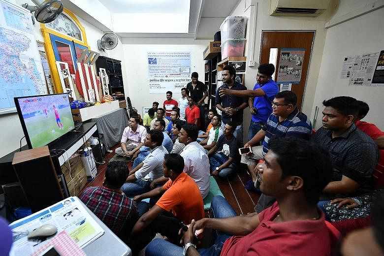 Foreign workers gathering at arts space Dibashram to catch the Costa Rica v Serbia match last night. The venue was provided by owner A.K.M. Mohsin, a Bangladeshi permanent resident. Muslim workers began their Hari Raya celebrations by going to the mo
