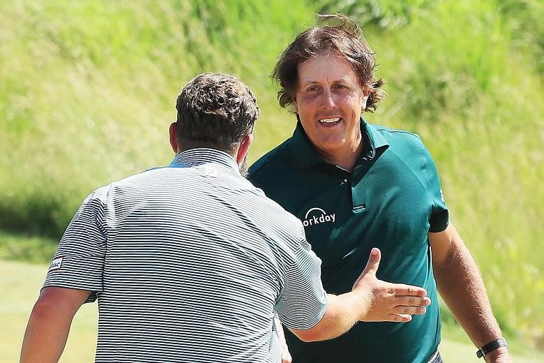 Andrew Johnston and Phil Mickelson shake hands on the 18th green during the third round of the US Open on Saturday. Johnston stopped short of condemning the American, who received a two-stroke penalty.