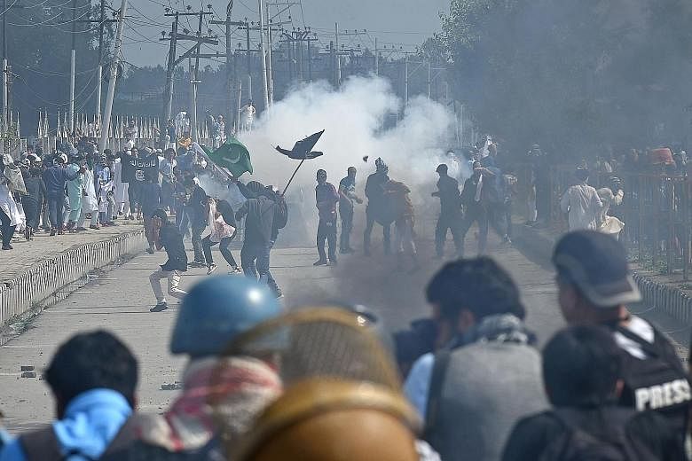 Indian police and paramilitary forces firing tear smoke shells and pellet guns at rock-throwing protesters