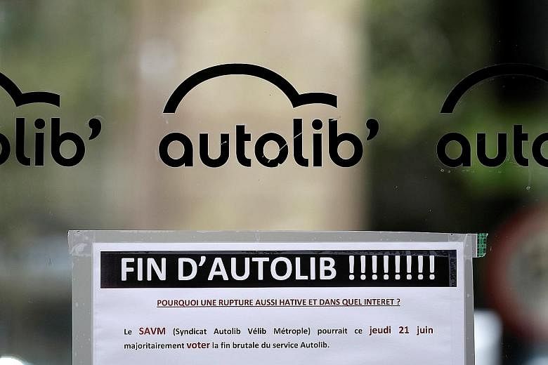 A flyer reading "The end of Autolib! Why such a hasty rupture and in what interest?" at an Autolib charging station in Paris last Thursday. Mayor of Paris Anne Hidalgo and Mr Vincent Bollore, head of the Bollore Group, posing with an Autolib car in 2