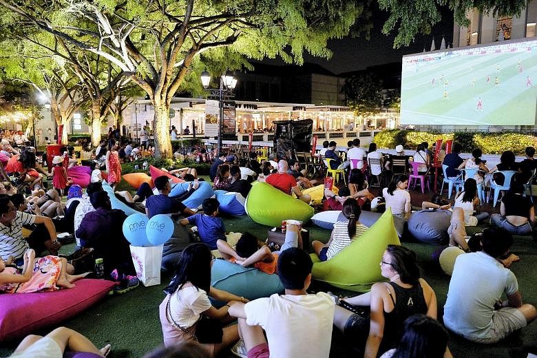 Football fans watching the World Cup match between Belgium and Tunisia at Chijmes last night. With the drama of the knockout rounds fast approaching, bigger crowds are expected at screening locations islandwide.
