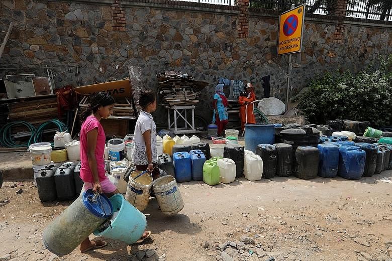People waiting to fill up containers with water from a tanker in Sanjay camp in New Delhi on Saturday. According to government think-tank Niti Aayog, demand for water will be twice the available supply by 2030. Water scarcity may also account for a 6