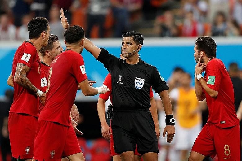 Paraguayan referee Enrique Caceres gesturing as he refers a penalty decision against Portugal to the VAR on Monday, amid the protests of the European champions' players.