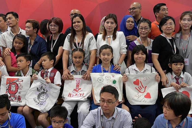 Above: Some of the young designers of this year's NDP funpacks displaying their creations at the launch event yesterday. The roughly 250,000 funpacks this year come in the form of tote bags to display the art clearly. Left: Funpack items include Sing