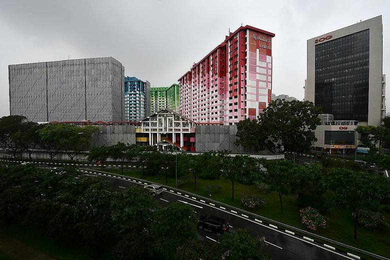 The demolition of the multicoloured Rochor Centre (above) began yesterday morning amid a rainstorm. Sound barriers (below, left) have been put up and the blocks will be demolished floor by floor (below, right).