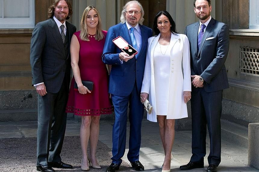 Singer and songwriter Barry Gibb with his wife Linda and their children, (from left) Michael, Alexandra and Ashley, after being knighted by Britain's Prince Charles at Buckingham Palace.