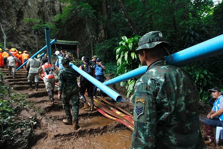 Thai military personnel carrying pipes to drain water from inside the flooded cave in northern Chiang Rai province, during the rescue operation yesterday. The underwater search had to be halted as water levels rose amid the relentless rainfall.