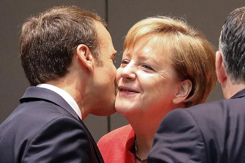 France's President Emmanuel Macron and Germany's Chancellor Angela Merkel share a light moment outside EU talks in Brussels yesterday.