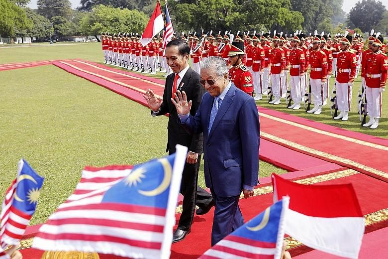 Malaysian Prime Minister Mahathir Mohamad and Indonesian President Joko Widodo greeting children with flags at Istana Bogor in West Java yesterday. Tun Dr Mahathir, who was on his second trip abroad since the May 9 polls, called Indonesia Malaysia's 