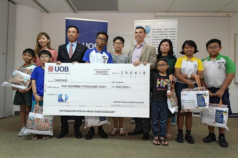 Seven beneficiaries of The Straits Times School Pocket Money Fund posed for a picture at yesterday's cheque presentation event with (from left) ST executive editor Sumiko Tan, Mr Eric Tham, Mr Warren Fernandez and STSPMF general manager Tan Bee Heong