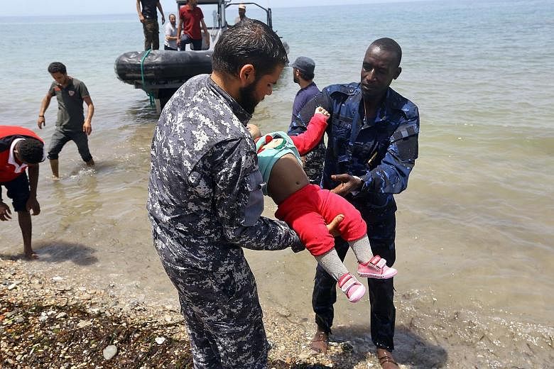 Members of the Libyan security forces carrying the body of a baby as survivors of the shipwreck off the coast of Libya were brought to shore in Al-Hmidiya, east of Tripoli, on Friday. Around 120 migrants were aboard the inflatable craft when it ran i