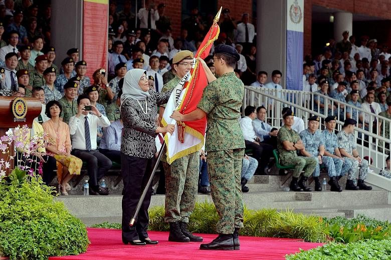 Colonel Paul Cheak, Chief Army Intelligence Officer, receiving the new Regimental Colours from President Halimah Yacob on behalf of the Headquarters Army Intelligence, as the Singapore Armed Forces (SAF) commemorated SAF Day at the Safti Military Ins