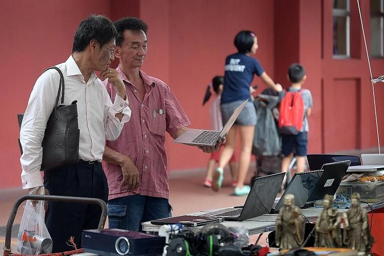 Mr Steven Low (second from left), 60, showing a laptop to a potential customer in Toa Payoh. He is among the former Sungei Road flea market vendors who have splintered across the island. Vendors hawking their wares at the Woodlands Recreation Centre,