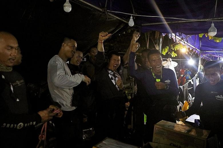 Members of Thailand's Navy Seals celebrating near the Tham Luang cave complex yesterday after the "Wild Boars" football team members (right, in a group photo recently) were found alive.