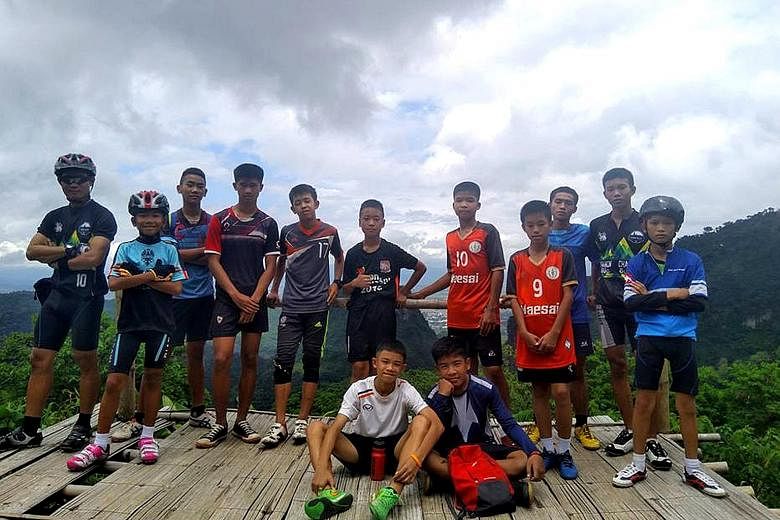 Members of Thailand's Navy Seals celebrating near the Tham Luang cave complex yesterday after the "Wild Boars" football team members (right, in a group photo recently) were found alive.