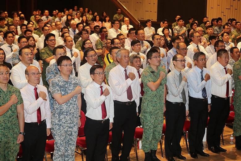 Defence Minister Ng Eng Hen (centre), flanked by Chief of Defence Force Lieutenant-General Melvyn Ong and SCCCI president Roland Ng, reciting the SAF Pledge with representatives from over 100 companies at Jurong Town Hall yesterday.
