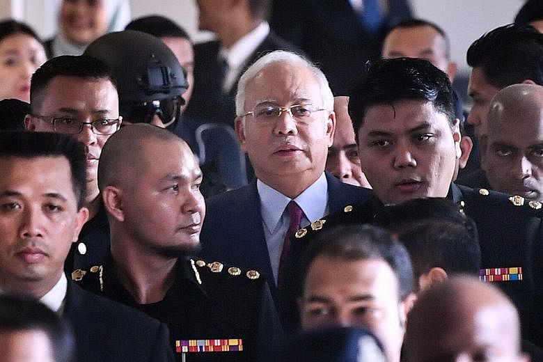 Former Malaysian prime minister Najib Razak under police escort after he was charged at the Kuala Lumpur High Court yesterday. His trial will take place in February and March next year.