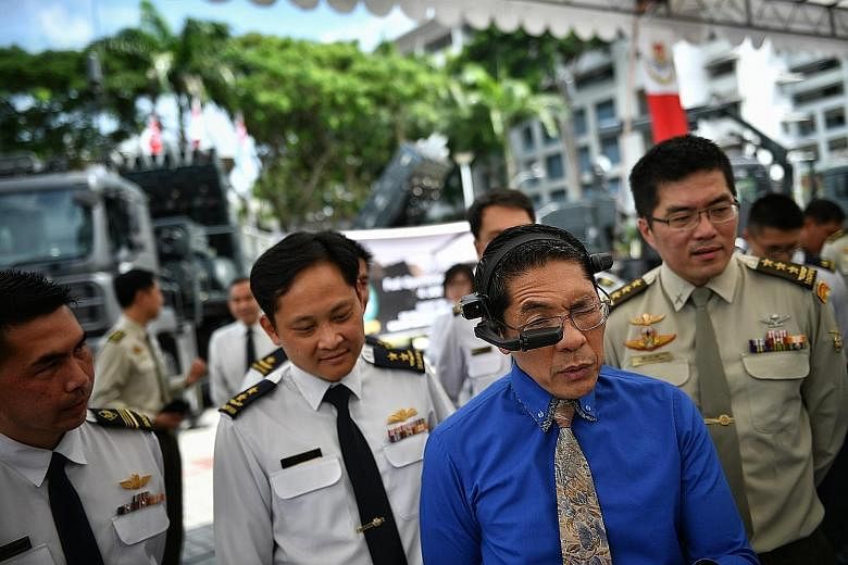 Senior Minister of State for Defence and Foreign Affairs Maliki Osman trying out the Spyder Remote Engineering Support smart glass. With him are Chief of Air Force Mervyn Tan (far left) and Chief of Defence Force Melvyn Ong. The Republic of Singapore