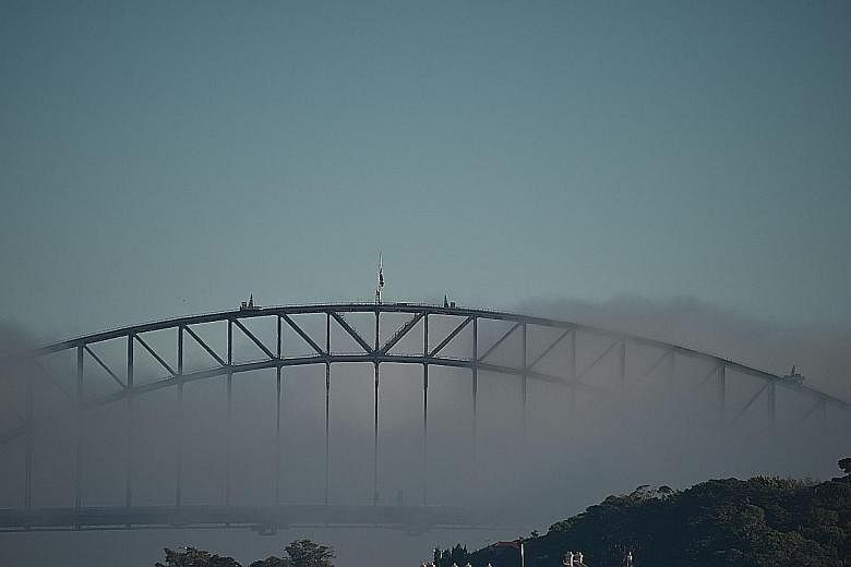 The Harbour Bridge nearly disappearing from sight as Sydney was shrouded in fog yesterday. Some flights were delayed or diverted, while ferry services were cancelled.