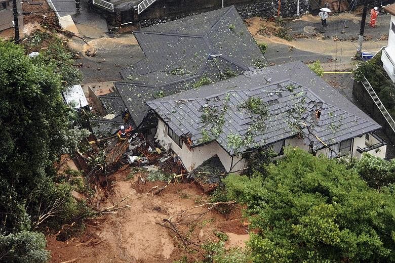 Above: The Togetsu bridge on the Katsura River in Kyoto yesterday. Right: Rescue workers at houses damaged by a landslide in Kitakyushu, southwestern Japan.