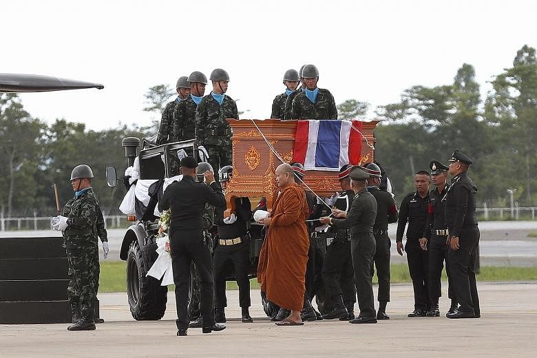 Left: A Thai Buddhist monk leading a military honour guard carrying the coffin of former Thai navy Seal diver Saman Kunan (above) at Mae Fah Luang international airport in Chiang Rai yesterday.