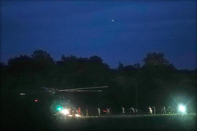 The boys who were rescued from Tham Luang cave being evacuated by medics and police officers at a helicopter pad in Chiang Rai province, on their way to a hospital, yesterday.