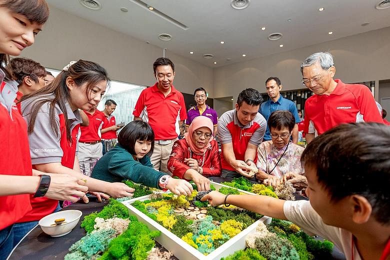 President Halimah Yacob (centre, seated), Keppel Corporation chairman Lee Boon Yang (right, standing) and Keppel CEO Loh Chin Hua (third from left, standing), join Keppel's beneficiaries from Monfort Care and Care Corner in a moss art activity.