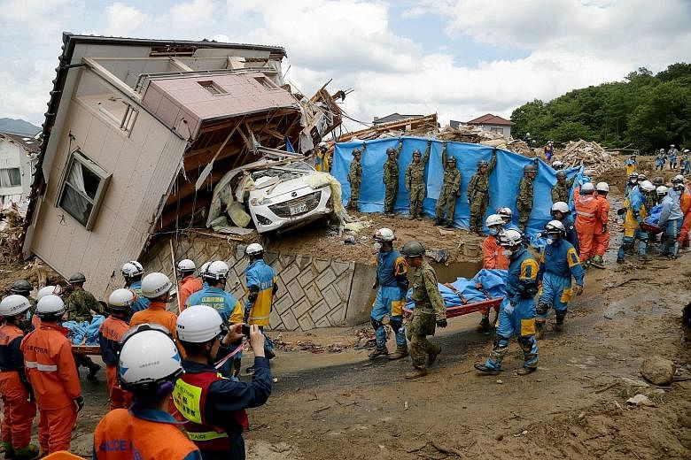 Japanese police and Self-Defence Force workers carrying a victim killed by a landslide caused by heavy rain in Kumano, Hiroshima prefecture, yesterday. Over 74,000 personnel, including police officers, firefighters and Self-Defence Force soldiers, ha