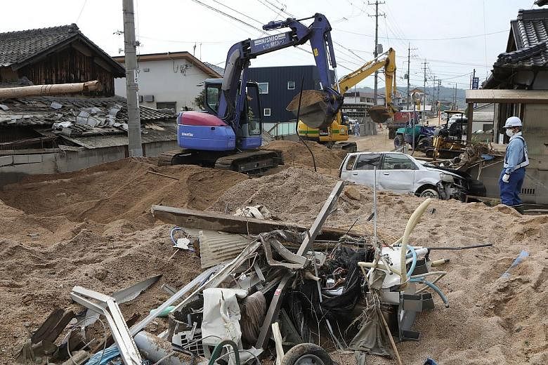 Workers yesterday clearing sediment in the residential area of Mabicho in Kurashiki, Okayama prefecture.
