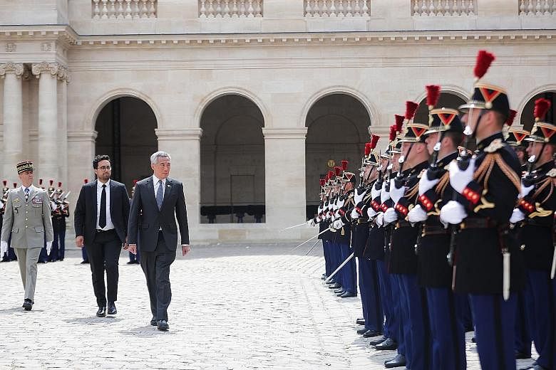 Prime Minister Lee Hsien Loong inspecting a guard of honour with France's Secretary of State for Digital Affairs Mounir Mahjoubi yesterday in Paris. He is in France at the invitation of French President Emmanuel Macron.