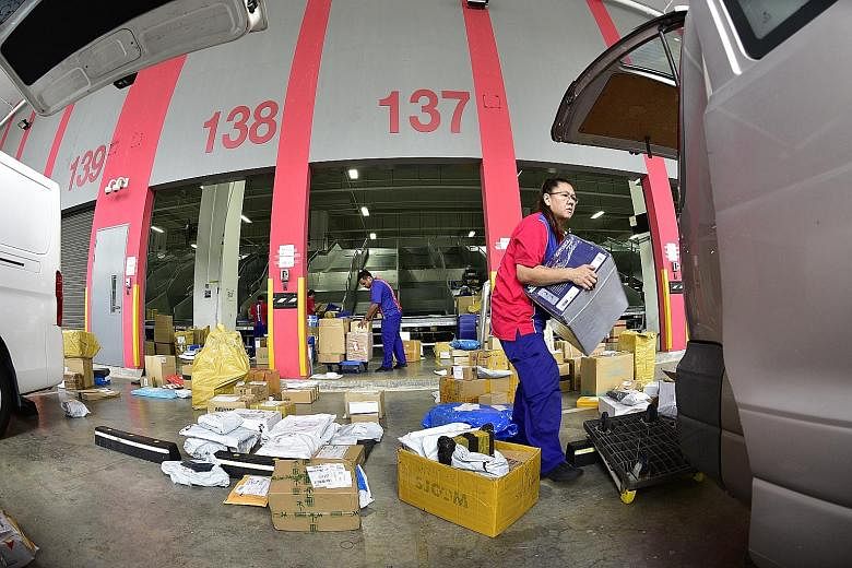 Couriers from SP Parcels check a parcel before it is placed in a delivery van. Speedpost is a last mile door-to-door express delivery service by SP Parcels, a subsidiary of SingPost. Couriers loading parcels containing customers' orders onto delivery