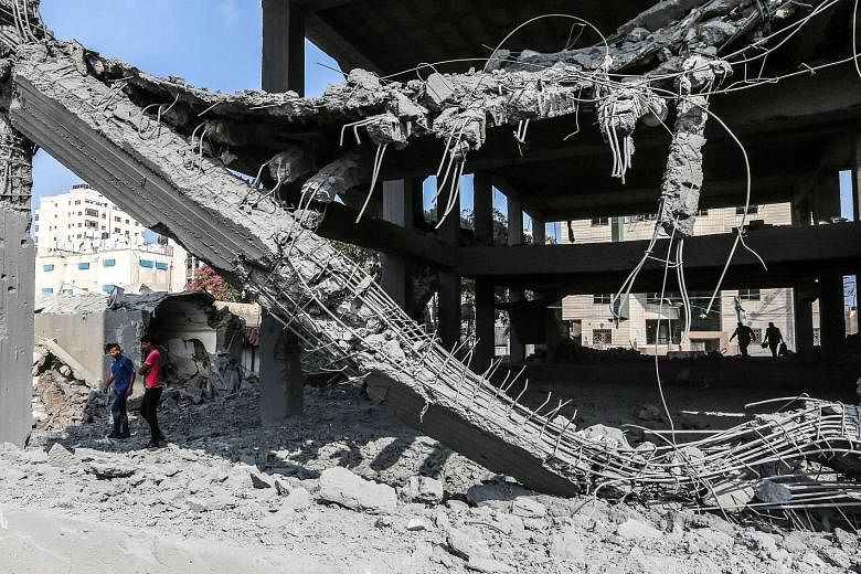 Young Palestinians walking through the wreckage of a building, damaged by Israeli air strikes in Gaza City, yesterday. Israel's military said the strikes targeted Hamas military facilities in the Gaza Strip, killing two Palestinians, while some 200 r