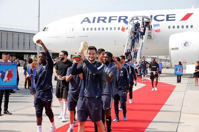 Above: Captain and goalkeeper Hugo Lloris holding the trophy as the French team arrived home yesterday after their World Cup victory. Left: Croatian national footballers greeting supporters as they rode in an open-top coach at Zagreb International Ai