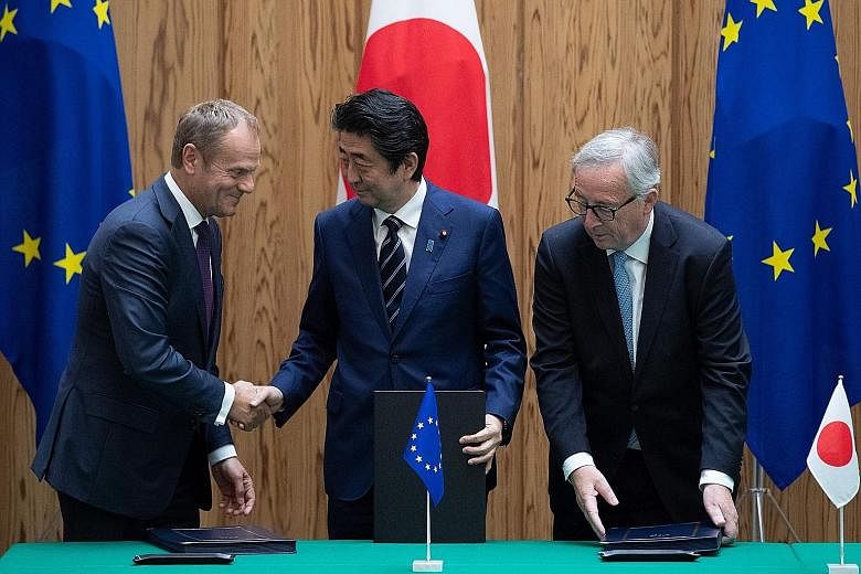 From left: European Council president Donald Tusk, Japan's Prime Minister Shinzo Abe and European Commission president Jean-Claude Juncker after the signing of the free trade deal in Tokyo yesterday.