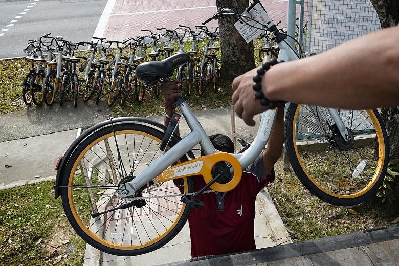 Top: A logistics company worker loading a lorry with oBike bicycles in Choa Chu Kang Avenue 3 earlier this month. Above: The discarded bikes at a recycling firm in Tuas last week. Compacted oBike bicycles (foreground) at a recycling firm in Sungei Ka