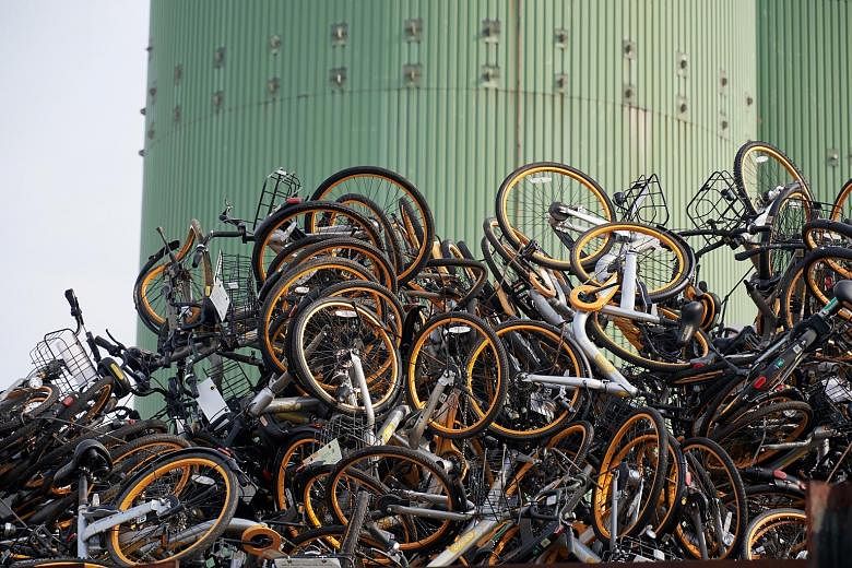 Top: A logistics company worker loading a lorry with oBike bicycles in Choa Chu Kang Avenue 3 earlier this month. Above: The discarded bikes at a recycling firm in Tuas last week. Compacted oBike bicycles (foreground) at a recycling firm in Sungei Ka