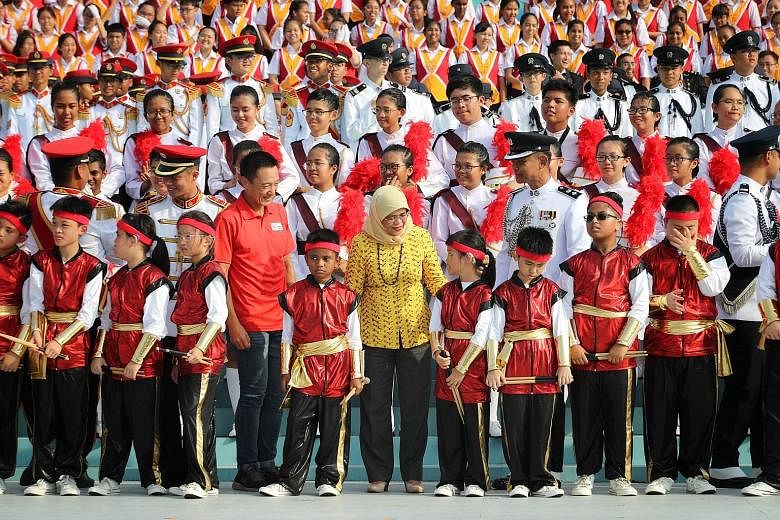 President Halimah Yacob with military tattoo members at a practice session yesterday. There are 220 combined schools choir members this year.